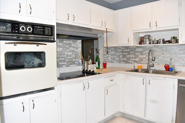 kitchen with black electric stovetop, white cabinetry, white oven, and sink