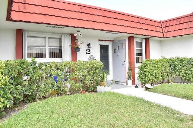 view of exterior entry featuring a porch and a lawn