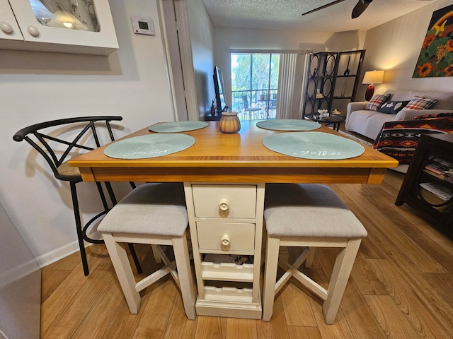 dining room with ceiling fan, a textured ceiling, and light hardwood / wood-style floors