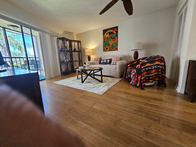 living room featuring a textured ceiling, hardwood / wood-style floors, and ceiling fan