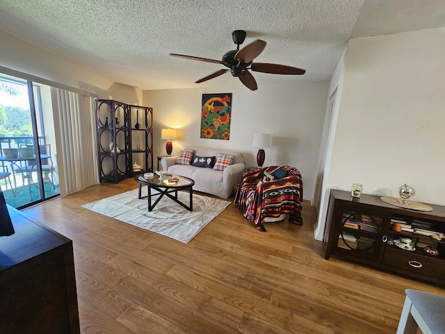 living room with a textured ceiling, ceiling fan, and hardwood / wood-style flooring