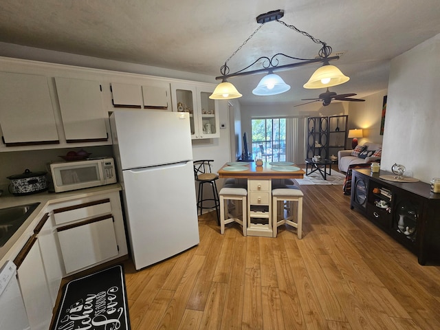 kitchen featuring ceiling fan, pendant lighting, white appliances, white cabinetry, and light hardwood / wood-style floors