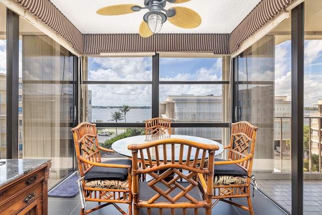 sunroom with a water view, ceiling fan, and a healthy amount of sunlight