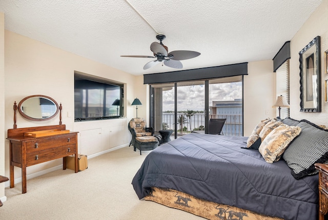 carpeted bedroom with ceiling fan, access to outside, and a textured ceiling