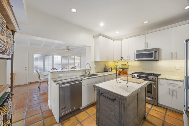 kitchen with appliances with stainless steel finishes, decorative backsplash, a kitchen island, and ceiling fan