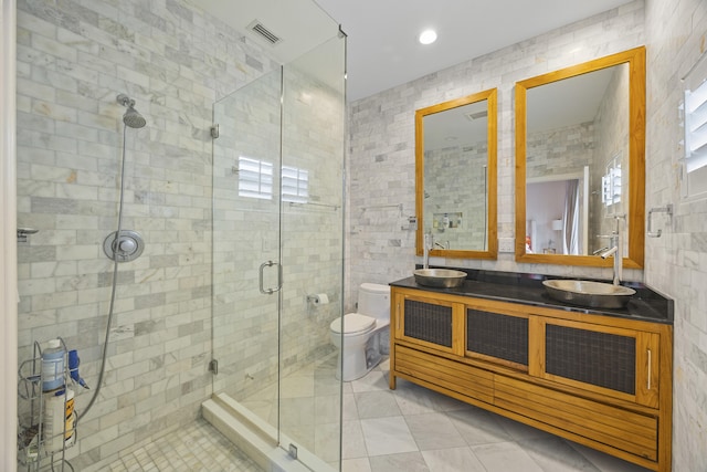 bathroom with tile walls, vanity, walk in shower, toilet, and tile patterned floors