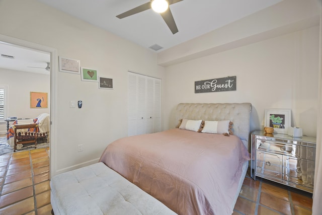 bedroom featuring ceiling fan, dark tile patterned flooring, and a closet