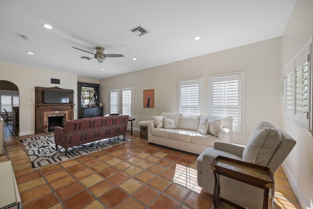 living room with tile patterned floors, ceiling fan, and a fireplace