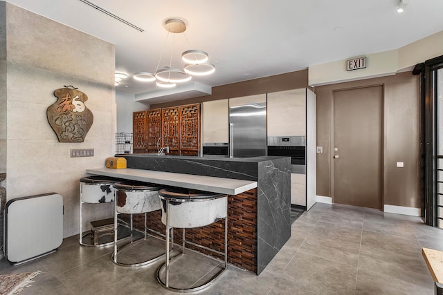 kitchen featuring kitchen peninsula, stainless steel appliances, tile walls, and a breakfast bar area