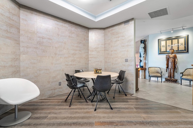 dining space featuring track lighting, tile walls, and hardwood / wood-style flooring