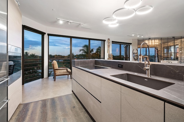 kitchen featuring decorative light fixtures, oven, sink, and light wood-type flooring