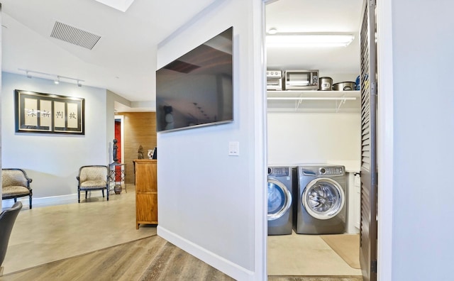 clothes washing area featuring washing machine and dryer and light hardwood / wood-style floors