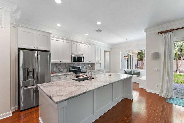 kitchen with stainless steel appliances, hanging light fixtures, sink, and white cabinetry