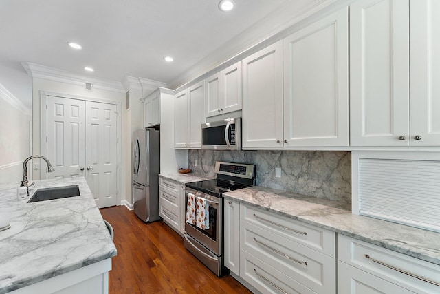 kitchen featuring dark hardwood / wood-style floors, sink, white cabinets, stainless steel appliances, and ornamental molding