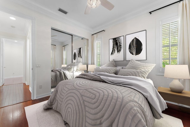 bedroom featuring ornamental molding, ceiling fan, dark wood-type flooring, and a closet