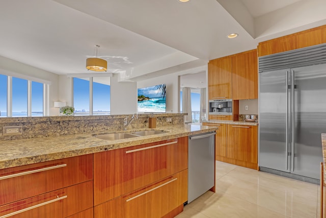 kitchen featuring pendant lighting, light stone counters, sink, stainless steel appliances, and light tile patterned floors