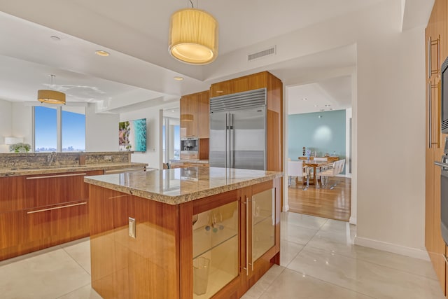 kitchen featuring hanging light fixtures, a breakfast bar, a center island, sink, and stainless steel built in fridge