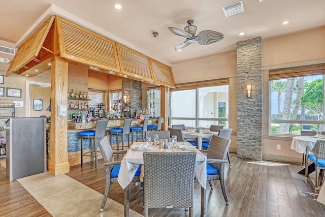 dining room featuring indoor bar, ceiling fan, and hardwood / wood-style floors