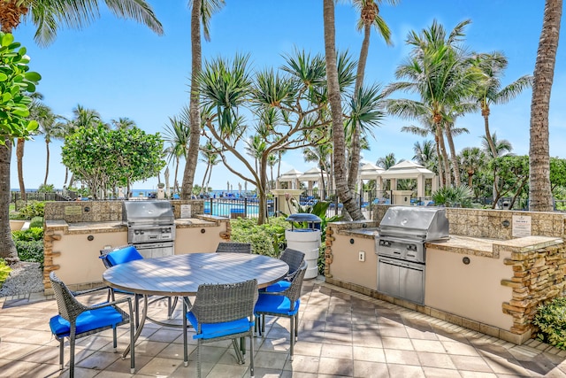 view of patio featuring area for grilling, a water view, and an outdoor kitchen