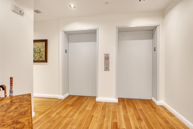 empty room with light hardwood / wood-style flooring and elevator