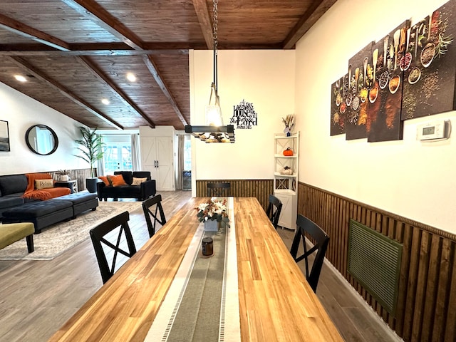 dining space with wooden ceiling, beam ceiling, hardwood / wood-style flooring, and wooden walls