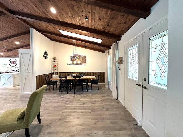 dining area with lofted ceiling with skylight, wooden walls, hardwood / wood-style floors, and wooden ceiling