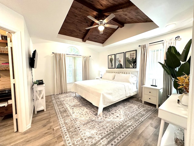 bedroom featuring ceiling fan, vaulted ceiling with beams, light hardwood / wood-style flooring, and wood ceiling