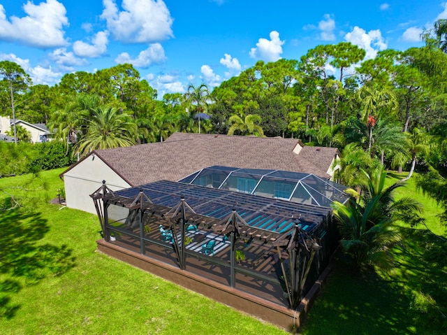 rear view of house with a patio, glass enclosure, a lawn, and a pool