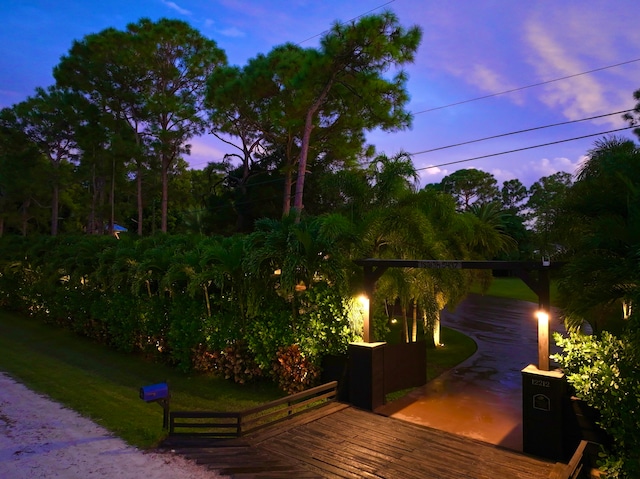 deck at dusk featuring a lawn