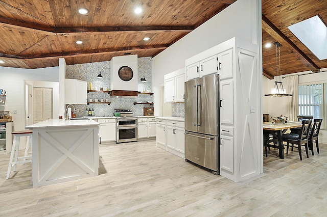 kitchen with pendant lighting, tasteful backsplash, light hardwood / wood-style flooring, white cabinets, and appliances with stainless steel finishes