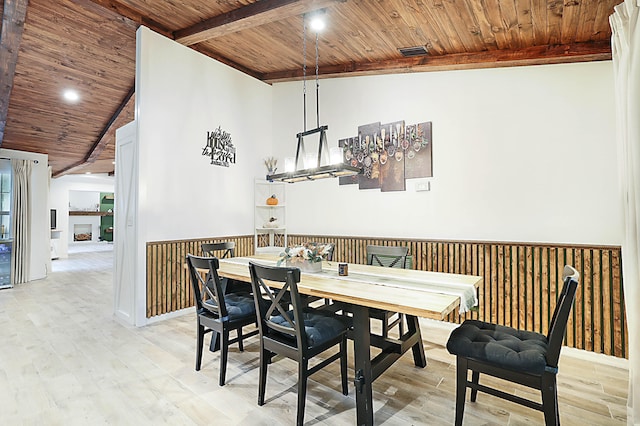 dining space with lofted ceiling, wooden walls, wooden ceiling, and light hardwood / wood-style flooring