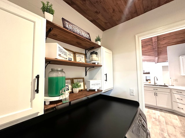 interior space with washer / dryer, wood ceiling, white cabinets, sink, and light hardwood / wood-style floors