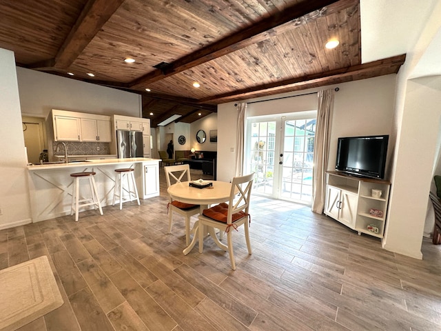 dining space featuring wood ceiling, lofted ceiling with beams, hardwood / wood-style flooring, and sink