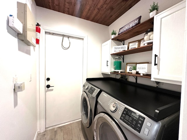 laundry area featuring independent washer and dryer, light hardwood / wood-style flooring, wood ceiling, and cabinets