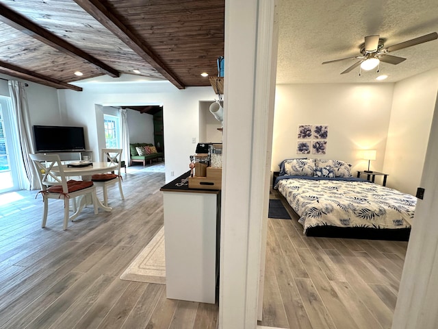 bedroom with beam ceiling, multiple windows, ceiling fan, and hardwood / wood-style floors