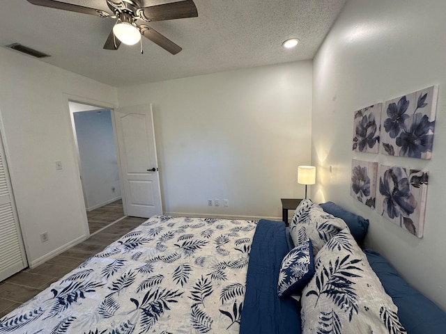 bedroom with hardwood / wood-style flooring, ceiling fan, and a textured ceiling