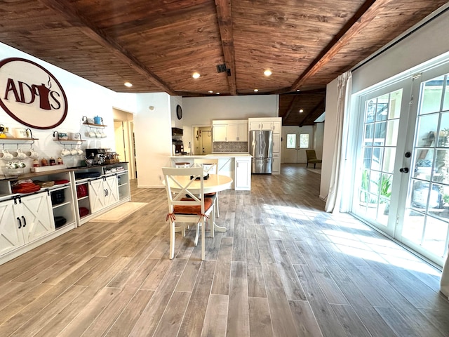 kitchen with beamed ceiling, stainless steel fridge, light wood-type flooring, wooden ceiling, and white cabinetry