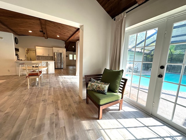 sitting room with light hardwood / wood-style floors, vaulted ceiling with beams, sink, and wood ceiling