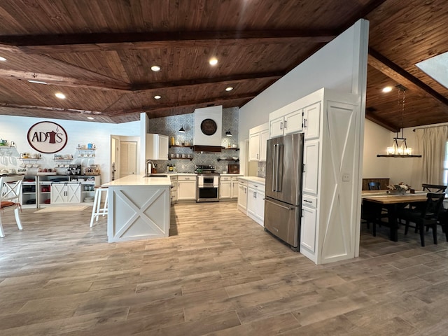 kitchen with appliances with stainless steel finishes, white cabinetry, a chandelier, and light hardwood / wood-style floors