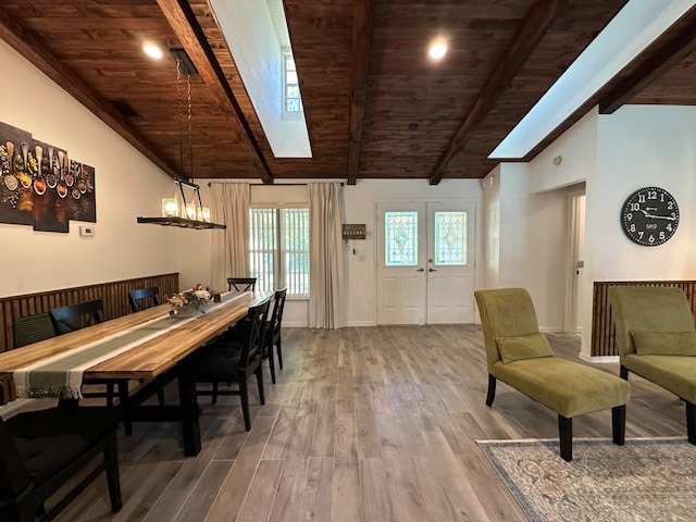 dining area featuring lofted ceiling with skylight, an inviting chandelier, hardwood / wood-style floors, and wood ceiling