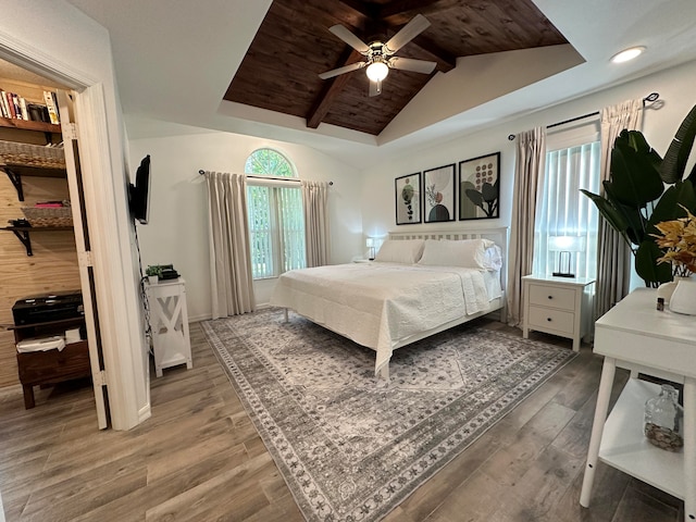 bedroom with ceiling fan, vaulted ceiling with beams, hardwood / wood-style flooring, and multiple windows