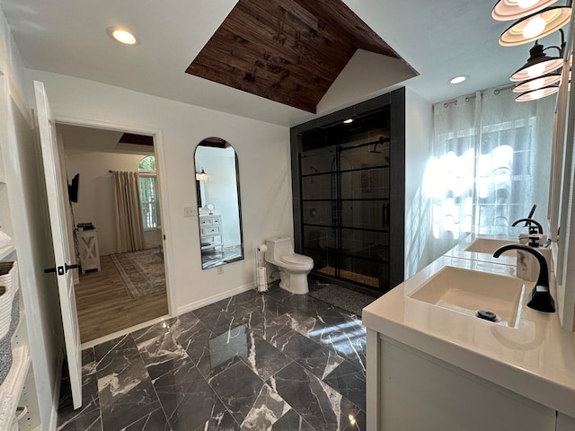 bathroom featuring wood-type flooring, vaulted ceiling, vanity, and toilet