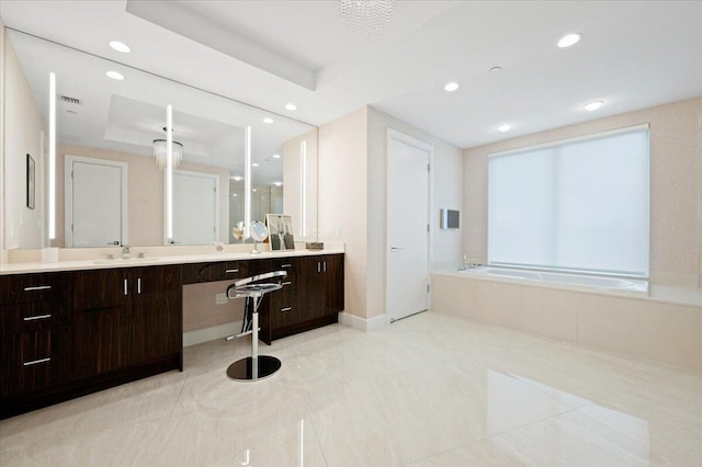 bathroom featuring a raised ceiling, vanity, and a bathing tub