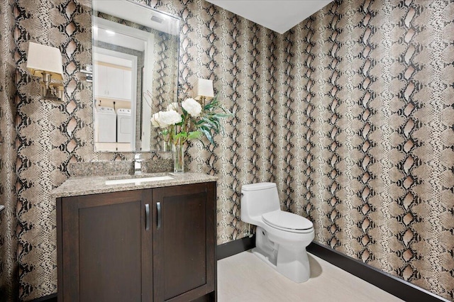 bathroom with curtained shower, separate washer and dryer, vanity, and toilet