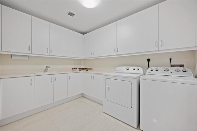 clothes washing area with cabinets, separate washer and dryer, and sink