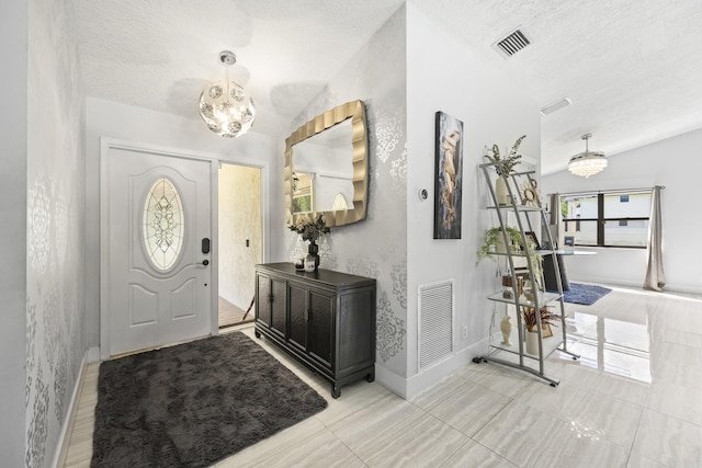 foyer featuring lofted ceiling, a textured ceiling, and a chandelier