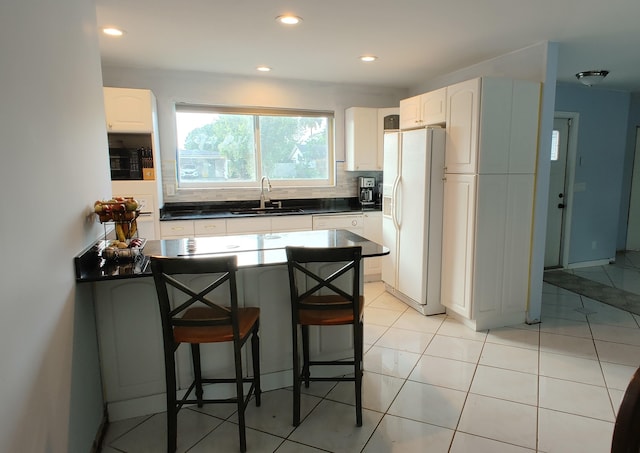 kitchen featuring tasteful backsplash, white cabinetry, a kitchen bar, sink, and white refrigerator with ice dispenser