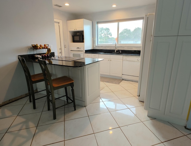 kitchen featuring white appliances, sink, kitchen peninsula, a kitchen breakfast bar, and white cabinets