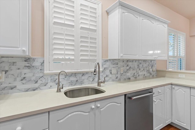 kitchen featuring dishwasher, sink, tasteful backsplash, and white cabinetry