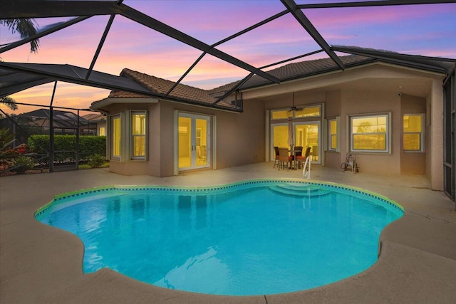 pool at dusk featuring glass enclosure, french doors, and a patio area